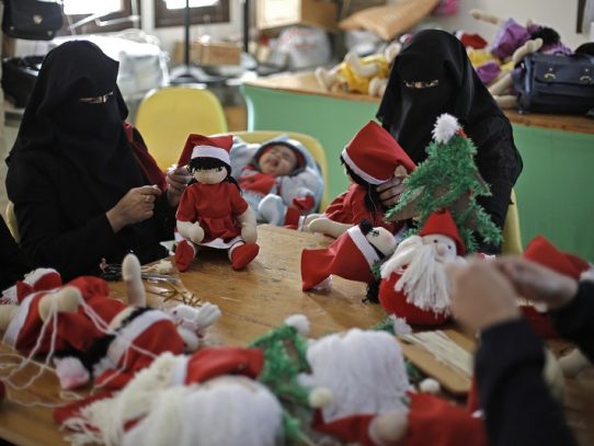 Palestinas vestidas con niqab fabrican muñecos de Papá Noel en Gaza